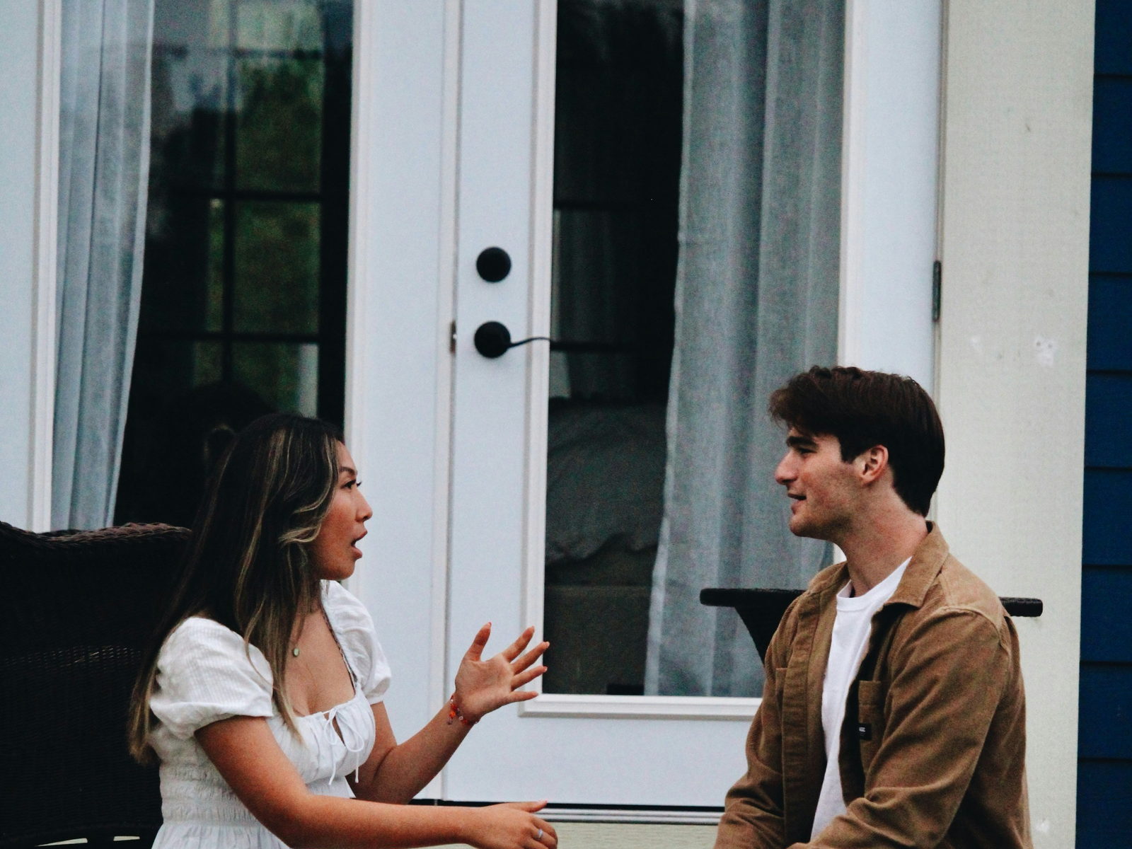 Two people sitting on the front steps of a house, talking